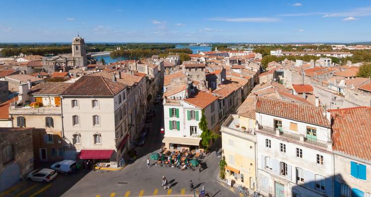 Vue aérienne d'une place de ville avec des cafés et une rivière au loin.