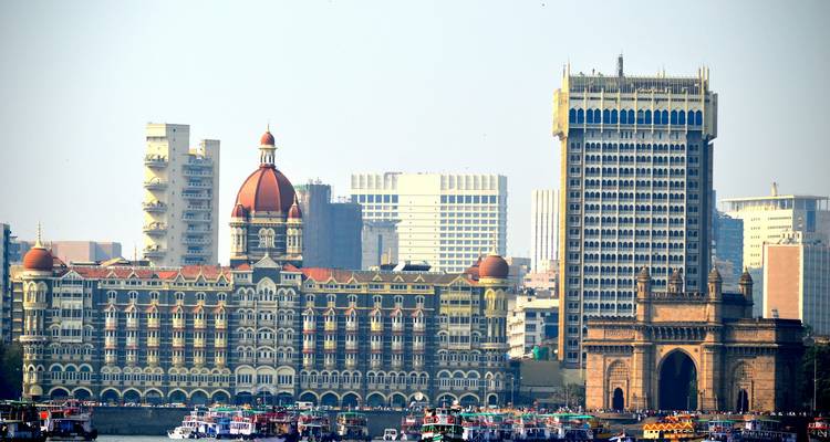 Skyline de Mumbai présentant l'hôtel Taj Mahal Palace et la Porte de l'Inde avec un port rempli de bateaux.