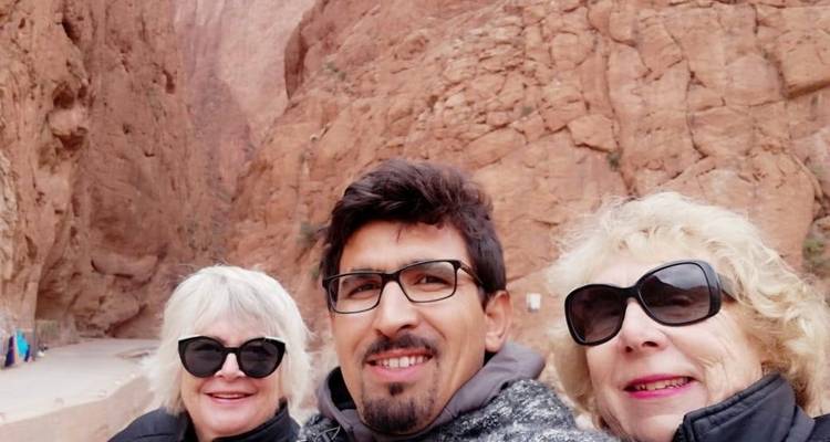 Three people smiling in a rocky landscape.