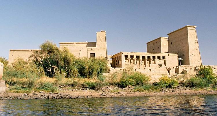 Tempelruinen entlang eines Flussufers mit Vegetation.