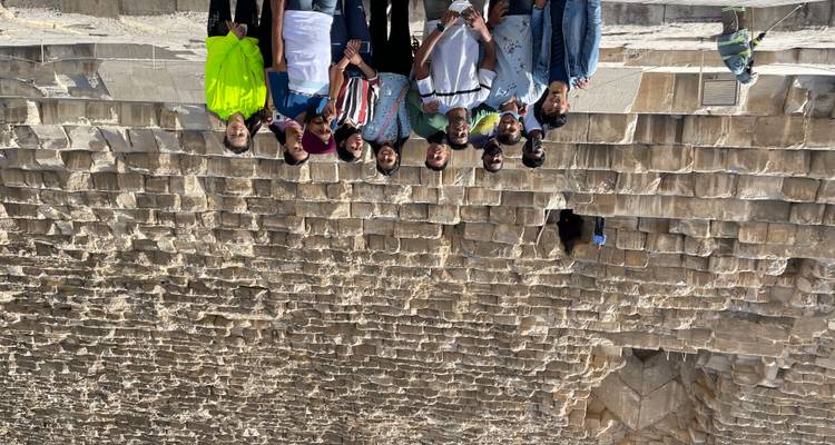 Gruppe von Menschen, die kopfüber vor Pyramiden posieren.