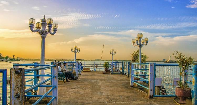 Schilderachtige pier met uitzicht op een meer bij zonsondergang met zittende mensen.