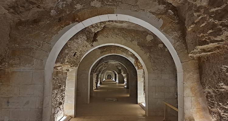 A long, arched stone corridor with symmetrical lighting.