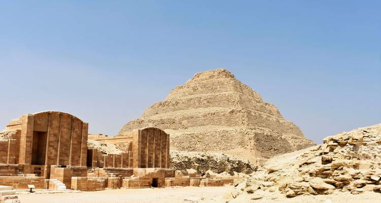 The step pyramid of Djoser in a sandy archaeological site.