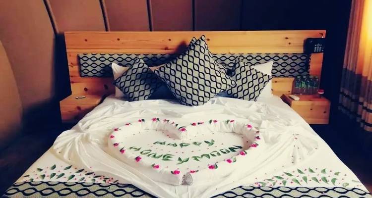 Dekoriertes Bett mit Blumen und einer „Glückliche Flitterwochen"-Nachricht.