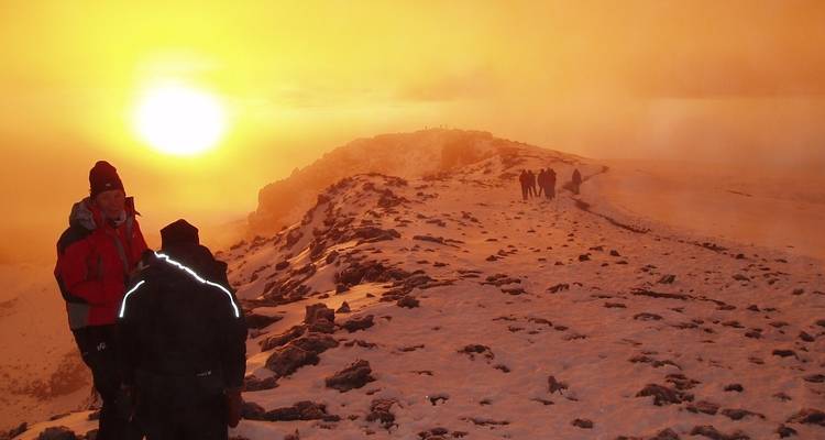Group of hikers at sunset on a snowy mountain.