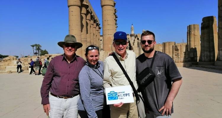 Touristen, die mit einem Schild an einer altägyptischen Stätte posieren.