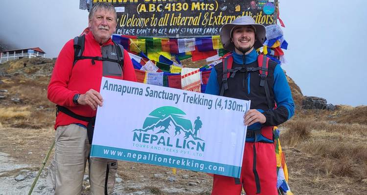 Deux randonneurs tenant une pancarte au camp de base de l'Annapurna.