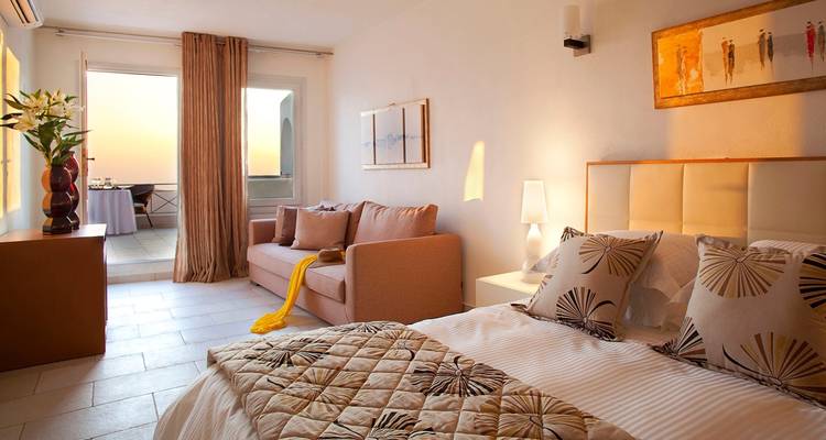 Chambre d'hôtel avec un lit double et un canapé, vue sur la mer.