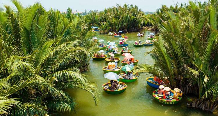 Los coloridos botes de mimbre navegan por una vía acuática angosta rodeada de densos bosques de nipa cerca de Hoi An.