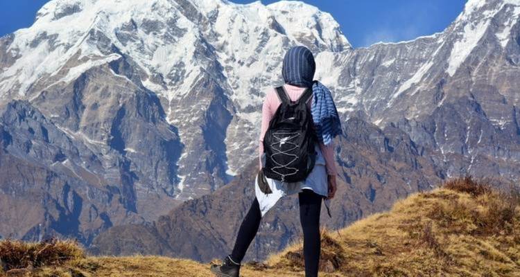 Reiziger met een rugzak die naar besneeuwde bergen kijkt.