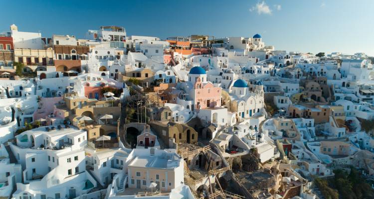 Vue aérienne des maisons troglodytiques blanches de Santorin sous un ciel lumineux.