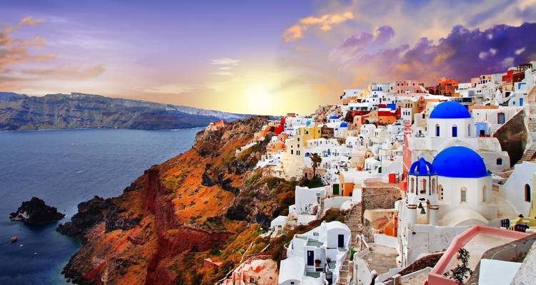 Vista del atardecer de Santorini con casas coloridas y un cielo dramático.