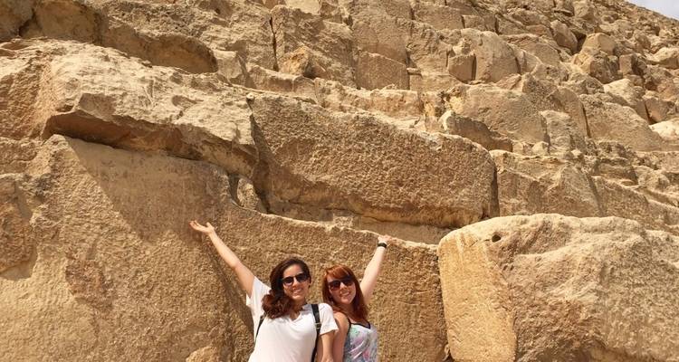 Toeristen die enthousiast poseren tegen massieve stenen blokken.