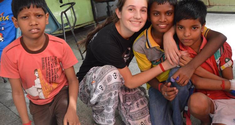 Un bénévole souriant accueille trois enfants du quartier dans un centre communautaire.