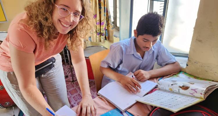 Un bénévole et un étudiant travaillent ensemble à un bureau avec des cahiers à l'intérieur d'une salle de classe.