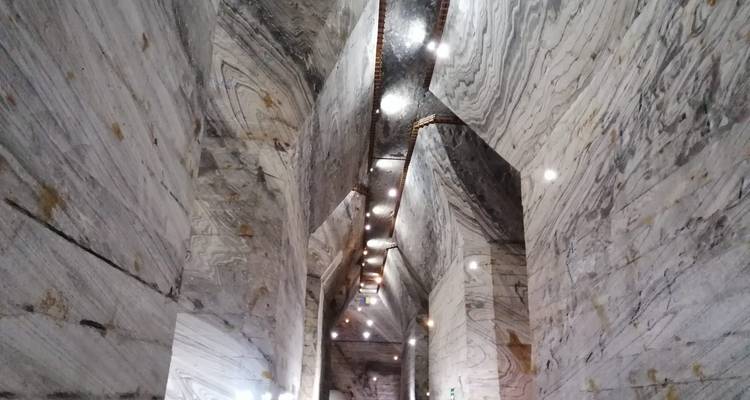 Lange, hoge ondergrondse kamer met gestreepte grijze marmeren wanden en dramatische verlichting.