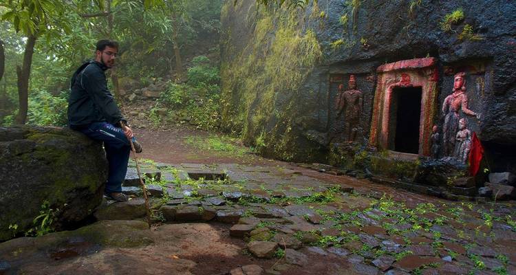 Mann, der in einer felsigen Landschaft in der Nähe von antiken Schnitzereien sitzt.