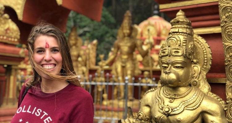 Frau lächelt neben kleinen goldenen Statuen.