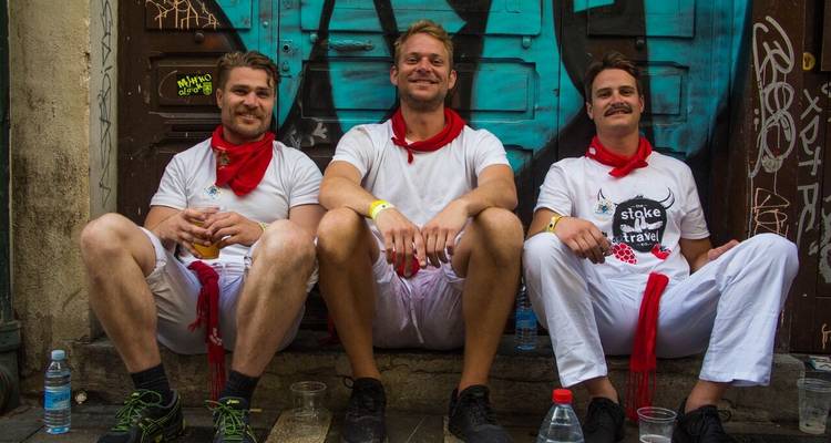 Trois hommes en vêtements blancs assis sur une marche, contre un mur tagué.