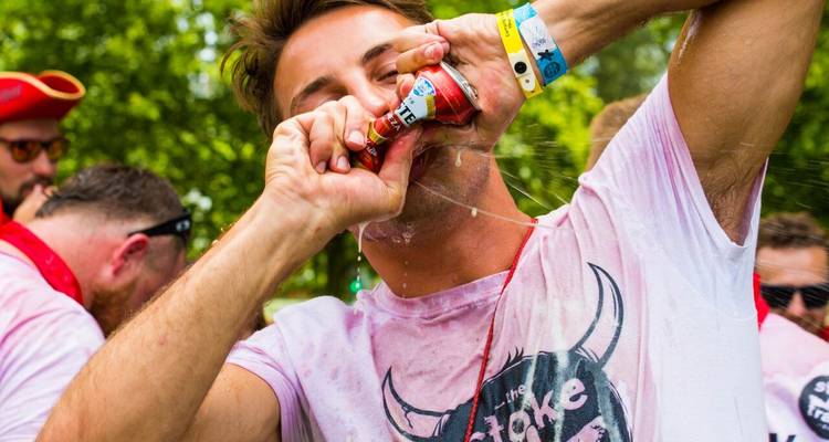 Une personne qui boit une canette de bière au goulot lors d'un festival.