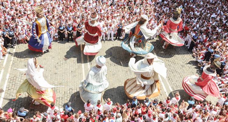 Des figures géantes défilant dans une foule festive.
