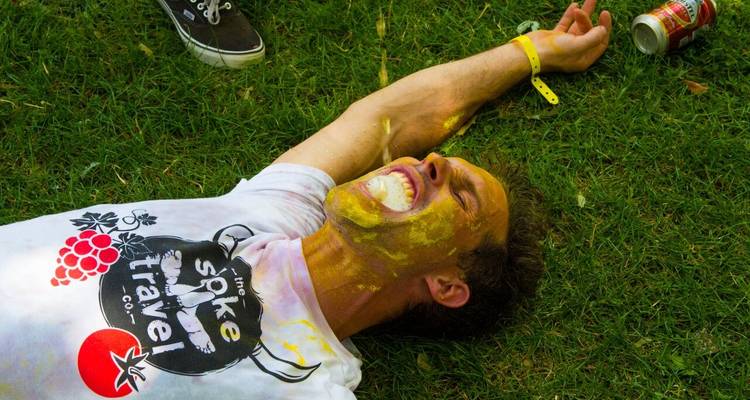 Un homme allongé sur l'herbe avec de la peinture jaune sur lui, souriant.