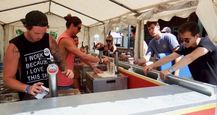 Groupe de personnes servant des boissons sous une tente.