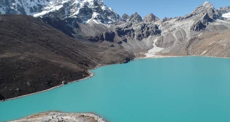 Turquoise gletsjermeer omringd door besneeuwde toppen.