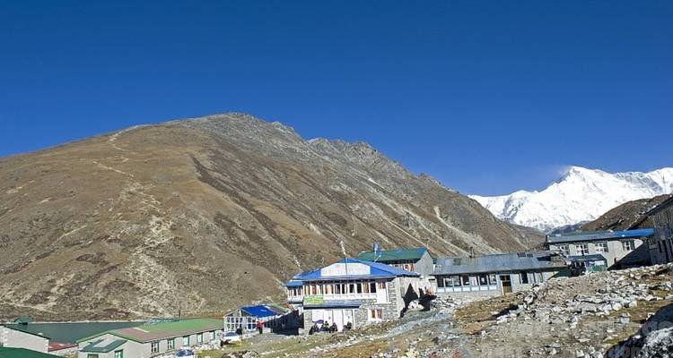 Afgelegen dorp met besneeuwde bergen en blauwe lucht.