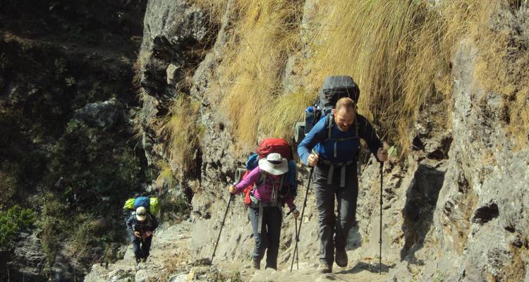 Hikers climbing a rocky path with backpacks.