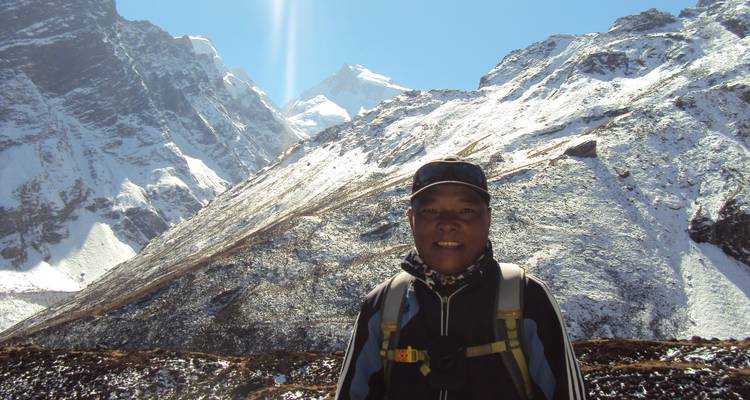 Person posing with a snowy mountain landscape in the background.