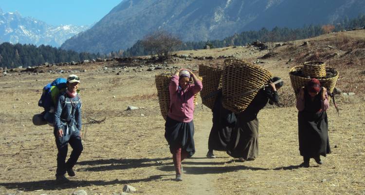 Group of locals carrying baskets and a tourist in hiking gear.
