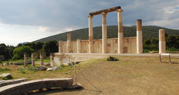 Ruines antiques avec des colonnes se détachant sur un paysage vallonné.