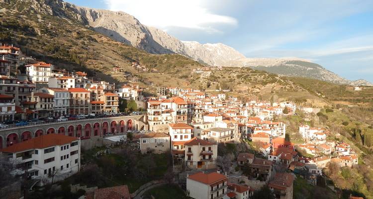 Ville pittoresque à flanc de colline avec des maisons aux toits rouges.