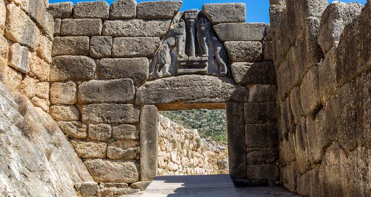 Massieve stenen poort met gebeeldhouwde leeuwen, oude ruïnes.
