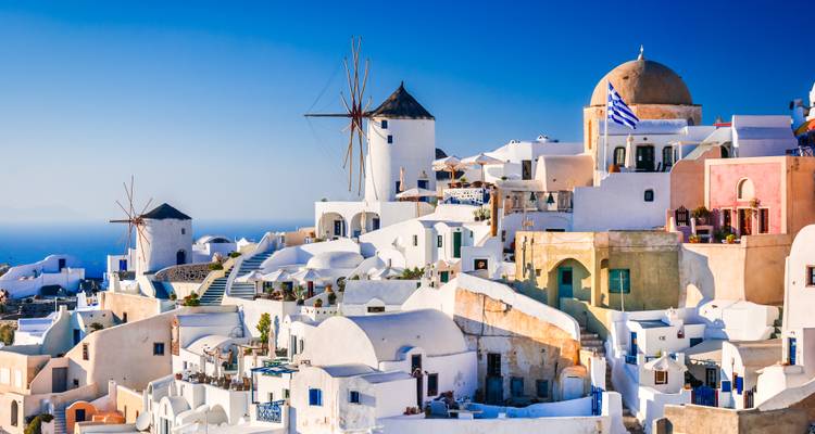 Witgekalkte gebouwen en windmolens in Santorini met blauwe lucht.