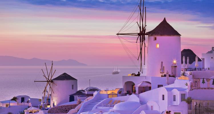 Windmolens in Santorini met een paarse zonsonderganglucht.