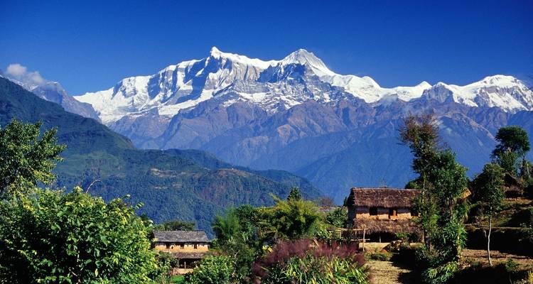 Rustiek dorp met besneeuwde bergen op de achtergrond.