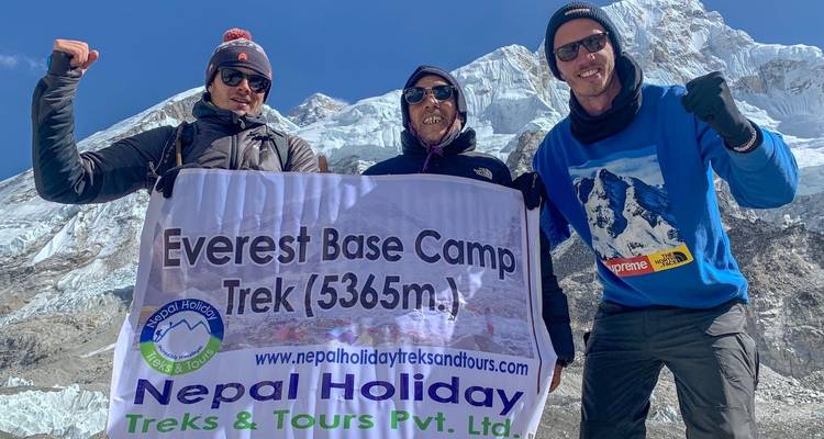 Drei Menschen mit einem Banner am Everest-Basislager.