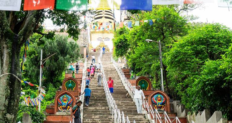 Des marches aux couleurs vives menant à un stupa avec des gens qui montent.