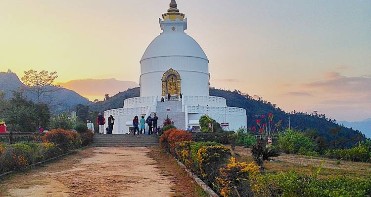 Stupa blanc avec des visiteurs et une vue sur le coucher de soleil.