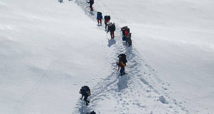 Groep trekkers die een met sneeuw bedekte route beklimmen.