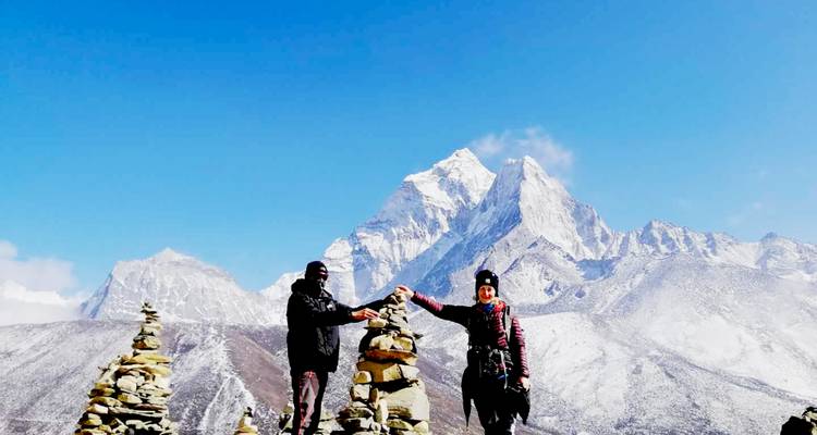 Twee mensen die poseren met steenmannetjes tegen een achtergrond van besneeuwde bergtoppen.
