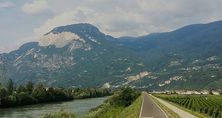 La pista de ciclismo sigue un valle fluvial bajo picos alpinos escarpados cerca de Trento.