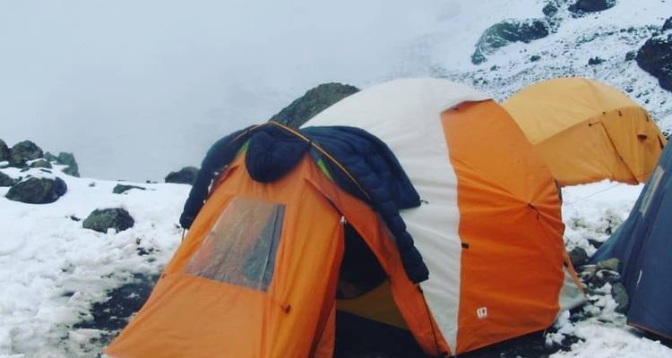 Tents set up in snowy, rocky terrain with foggy background.