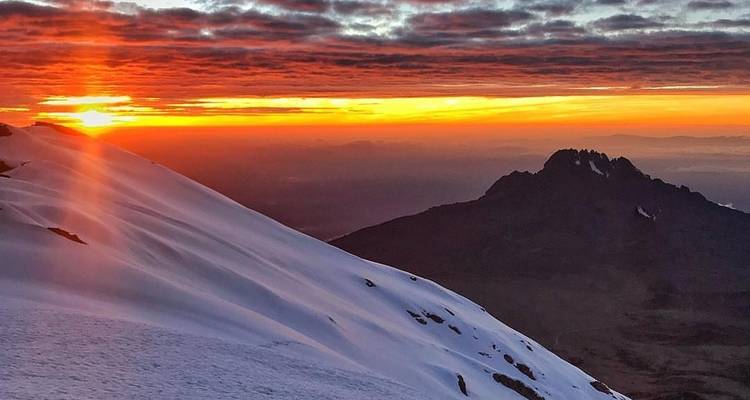 Sunset over a snowy mountain ridge with colorful sky.