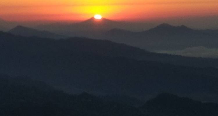 Sonnenaufgang über den Silhouetten von Bergketten.