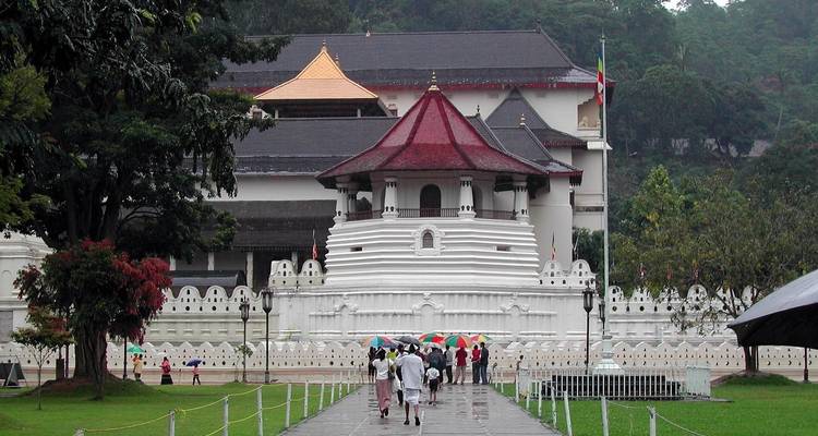 Temple with people carrying umbrellas in the rain.