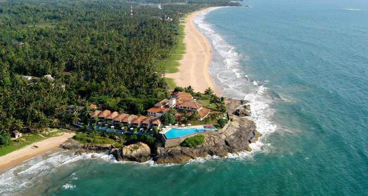 Aerial view of a coastal resort with a pool and beach.